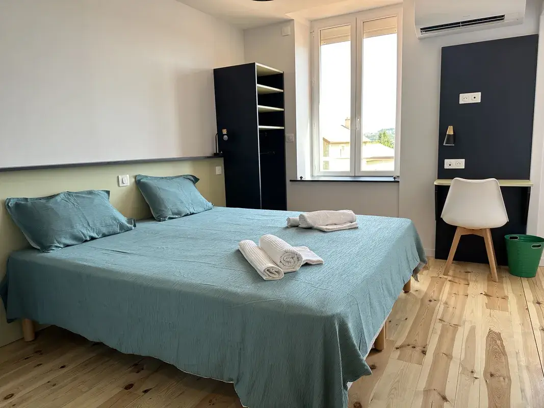 Chambre parentale du gîte La Bamboche à Lapte avec lit double, bureau, penderie et décoration moderne.